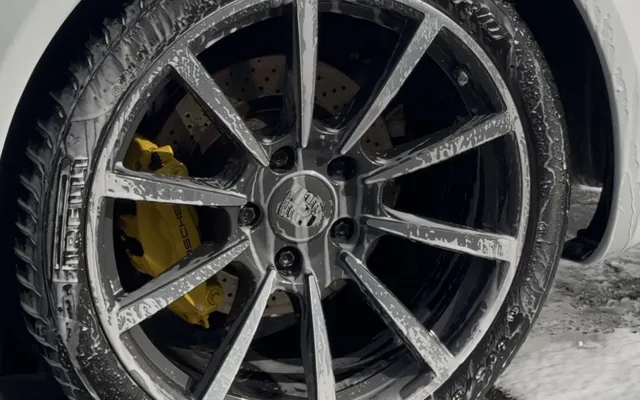 A foamed wheel with yellow calipers mid-wash