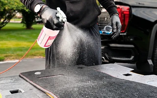 Andrew deep-cleaning a floor mat outside the car