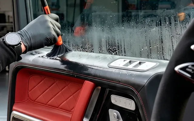 A detailing brush working the crevices of a door panel