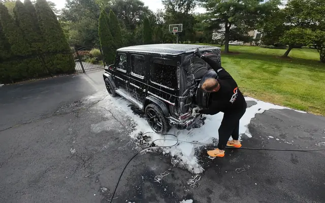 Andrew washing a foam-covered Mercedes-AMG G63 on a residential driveway
